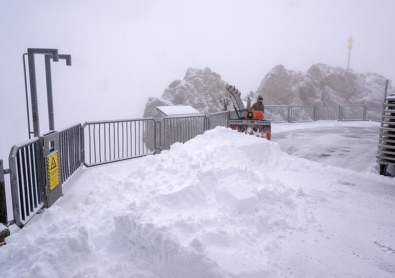 Eine Frau räumt den Neuschnee auf der Aufsichtsplattform der Zugspitze.