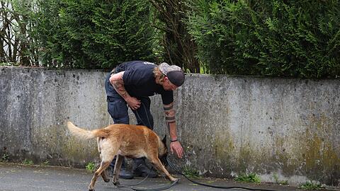 Ein Polizist sucht mit einem Sp&uuml;rhund nach Hinweisen.