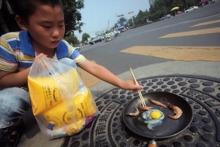 Die Hitzewelle hat  die Gulli-Deckel so stark erhitzt, dass die Chinesen sie als Herdplatte benutzen und auf ihnen Eier und Garnelen braten. Foto: Zheng Tao