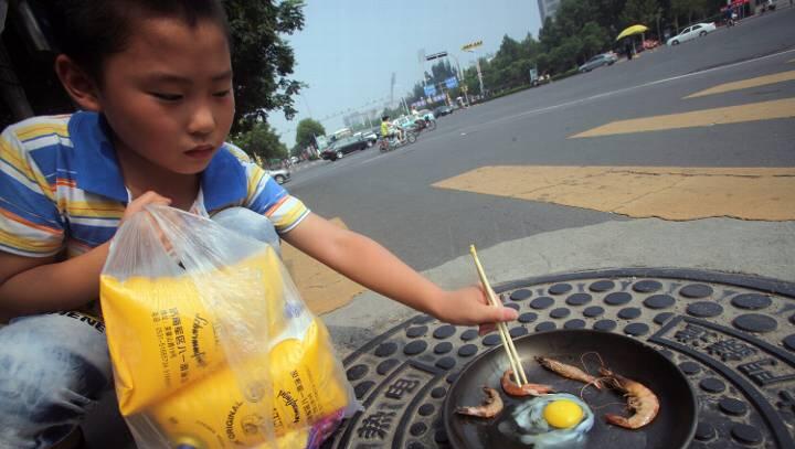 Die Hitzewelle hat die Gulli-Deckel so stark erhitzt, dass die Chinesen sie als Herdplatte benutzen und auf ihnen Eier und Garnelen braten. Foto: Zheng Tao Die Hitzewelle hat die Gulli-Deckel so stark erhitzt, dass die Chinesen sie als Herdplatte benutzen und auf ihnen Eier und Garnelen braten. Foto: Zheng Tao