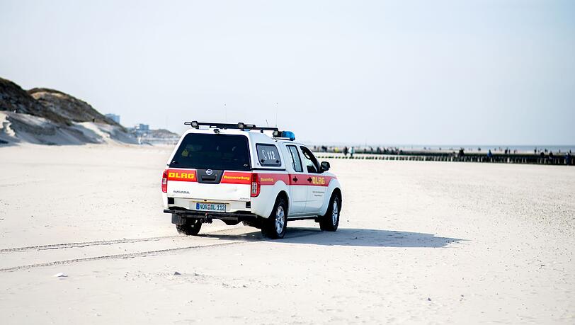Ein Einsatzfahrzeug der DLRG Wasserrettung fährt über einen Strand.