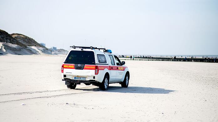 Ein Einsatzfahrzeug der DLRG Wasserrettung fährt über einen Strand.