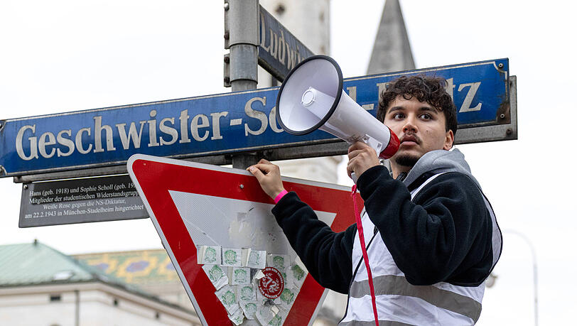 Ein Demonstrationsteilnehmer in Warnweste spricht am Geschwister-Scholl-Platz durch ein Megafon zu den Versammelten. Die Initiative Gen Z regelt hat bundesweit in vielen Städten zu Protesten für mehr Klimaschutz, gegen steigende Lebenshaltungskosten und gegen die Wehrpflicht aufgerufen. Ein Demonstrationsteilnehmer in Warnweste spricht am Geschwister-Scholl-Platz durch ein Megafon zu den Versammelten. Die Initiative Gen Z regelt hat bundesweit in vielen Städten zu Protesten für mehr Klimaschutz, gegen steigende Lebenshaltungskosten und gegen die Wehrpflicht aufgerufen.
