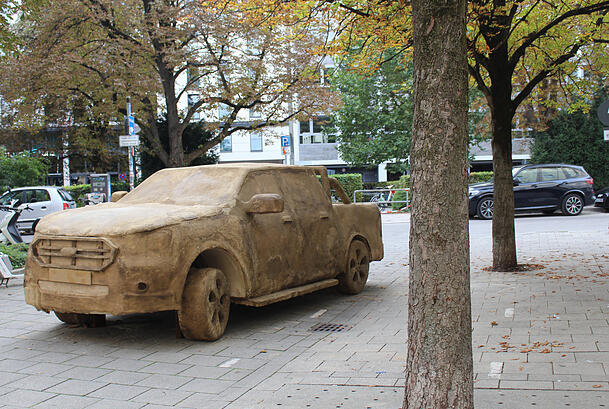 Die Kunst und im Hintergrund ein Original: Drei solcher Moder-SUVs stehen nun ein Jahr lang in München und verrotten immer mehr. Sie sollen eine Diskussion über den Autoverkehr in der Stadt auslösen