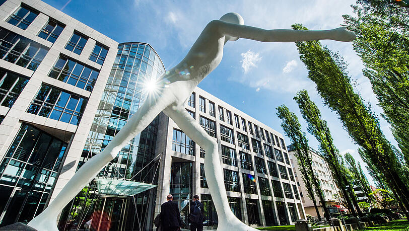 Mitarbeiter gehen an der Statue &bdquo;Walking Man&ldquo; vorbei in die Zentrale der Munich Re. Berufseinsteiger erhalten dort mindestens ein Bruttogehalt in H&ouml;he von 3145 Euro im Monat.