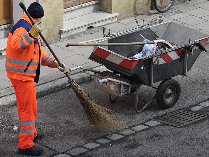 Ein Mitarbeiter der Straßenreinigung fegt eine Straße in Bamberg mit einem Reisigbesen. Foto: David-Wolfgang Ebener/dpa/Archivbild