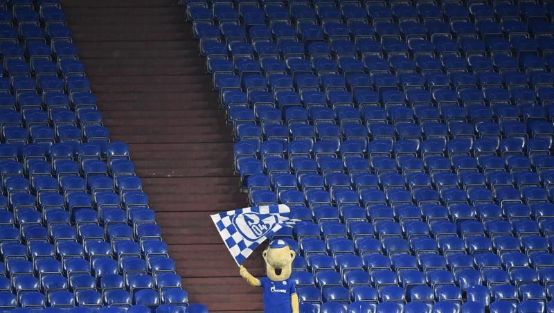 Schalke-Maskottchen Erwin schwenkt auf der sonst leeren Tribüne während des Revierderbys eine Fahne.