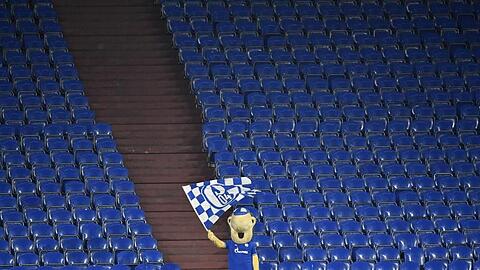 Schalke-Maskottchen Erwin schwenkt auf der sonst leeren Tribüne während des Revierderbys eine Fahne.