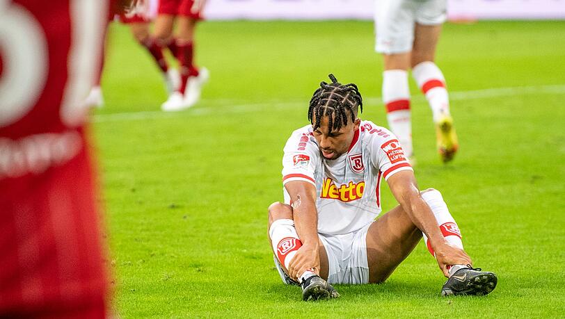 Regensburgs Leon Guwara sitzt nach dem Tor zum 1:0 auf dem Rasen.