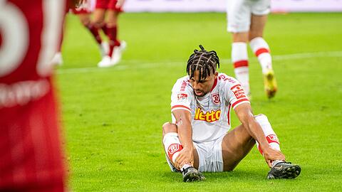 Regensburgs Leon Guwara sitzt nach dem Tor zum 1:0 auf dem Rasen.