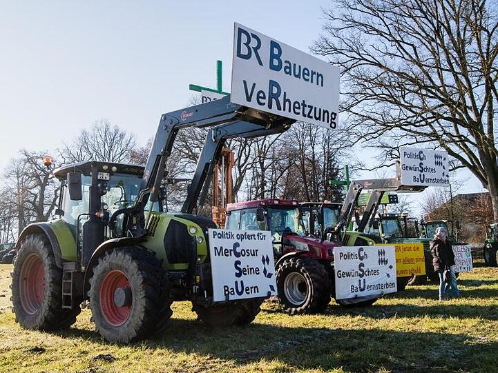 An Traktoren demonstrierender Landwirte hängen Schilder mit Aufschriften wie "BR Bauern Verhetzung". Foto: Matthias Balk/dpa