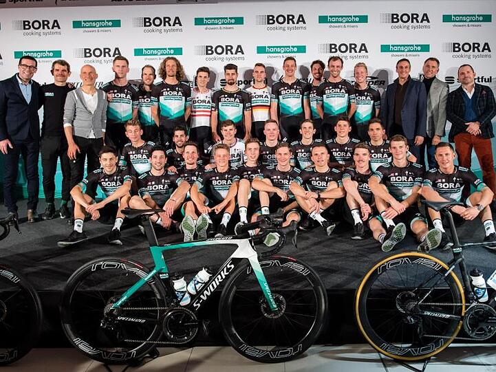 Ralph Denk (hinten, 2.v.l.), Teammanager des Radsportteams von Bora-hansgrohe, und das Team stellen sich bei der Vorstellung des Radsportteams für das Jahr 2020 auf der Bühne zum Gruppenfoto auf. Foto: Matthias Balk/dpa/Archivbild