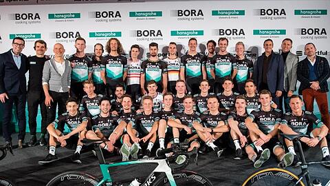 Ralph Denk (hinten, 2.v.l.), Teammanager des Radsportteams von Bora-hansgrohe, und das Team stellen sich bei der Vorstellung des Radsportteams für das Jahr 2020 auf der Bühne zum Gruppenfoto auf. Foto: Matthias Balk/dpa/Archivbild