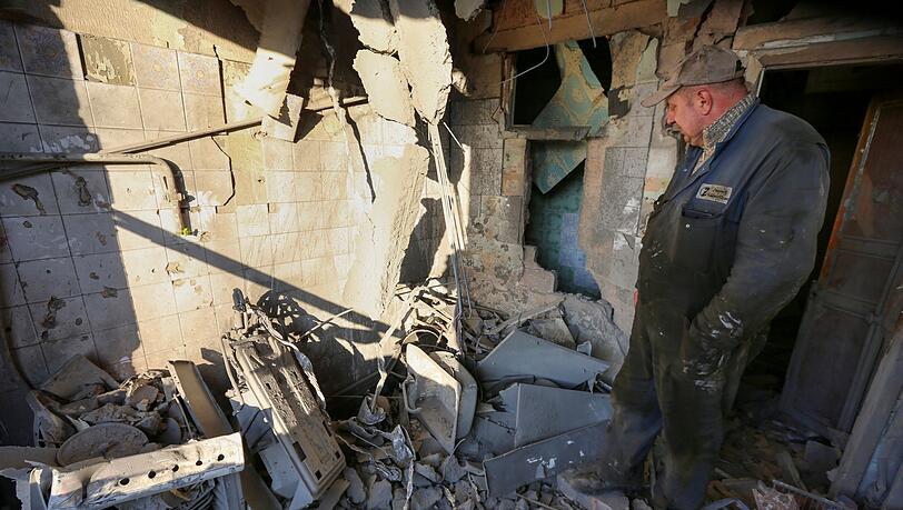 Ein Mann untersucht ein durch Beschuss beschädigtes Wohnhaus. Die Ukraine meldet erneut neue Raketenangriffe.