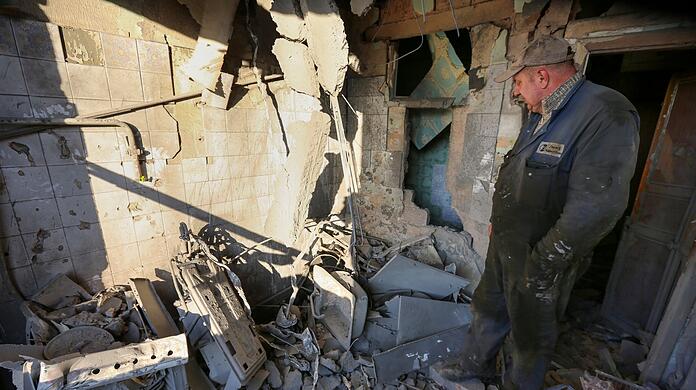 Ein Mann untersucht ein durch Beschuss beschädigtes Wohnhaus. Die Ukraine meldet erneut neue Raketenangriffe.