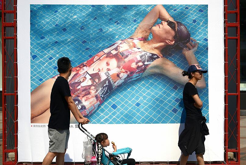 Eine Familie geht in Peking an einem Werbeplakat vorbei. An diesem "Tag der Arbeit" werden sehr viele Touristen in der Hauptstadt erwartet.