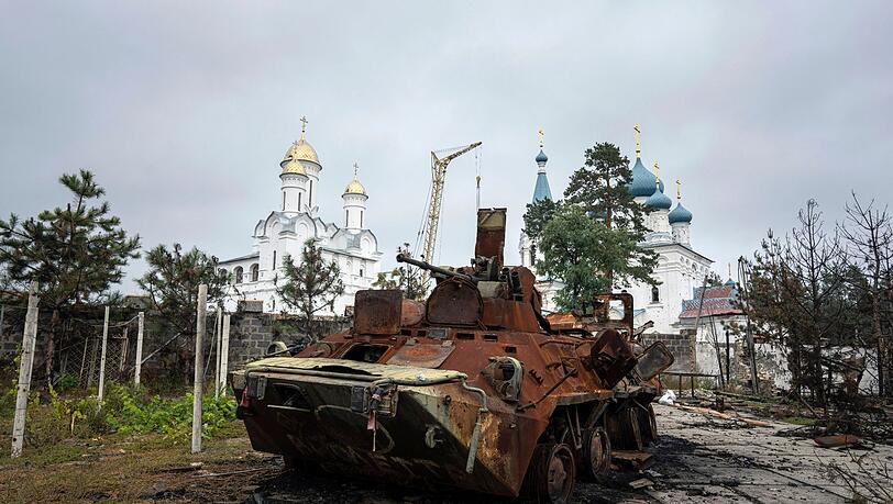 Ein zerstörter russischer Schützenpanzer steht vor einer Kirche in Isjum.