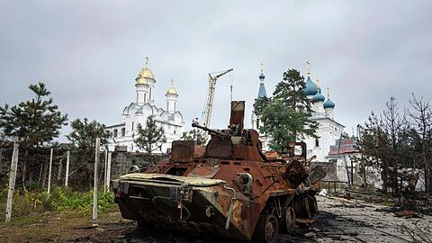 Ein zerstörter russischer Schützenpanzer steht vor einer Kirche in Isjum.