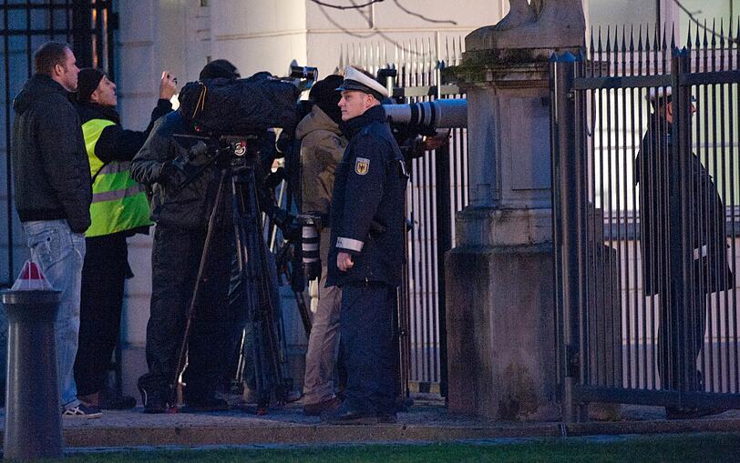 Ein Polizist steht am Mittwoch (04.01.12) am Schloss Bellevue in Berlin vor wartenden Journalisten.