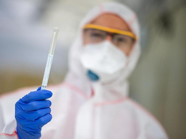 Ein Mitarbeiter hält in einem Abstrichzentrum einen Coronatest-Abstrich in der Hand. Foto: Sebastian Gollnow/dpa/Symbolbild
