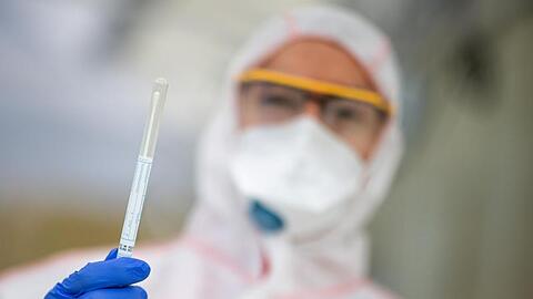Ein Mitarbeiter hält in einem Abstrichzentrum einen Coronatest-Abstrich in der Hand. Foto: Sebastian Gollnow/dpa/Symbolbild