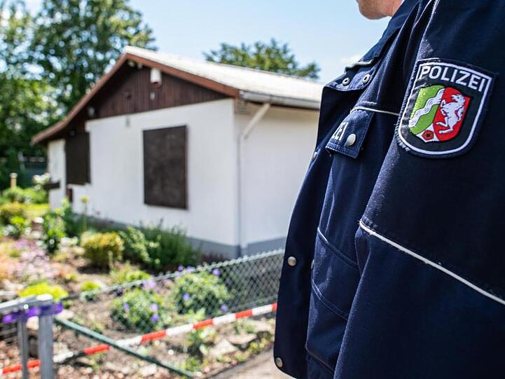 Ein Polizeibeamter steht vor der Gartenlaube in Münster, wo der vermutliche Haupttäter Teile seiner Server-Anlage unterbrachte.