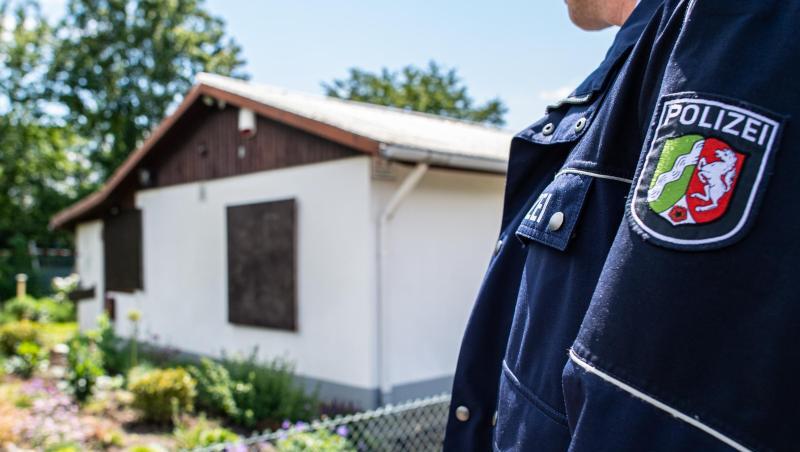 Ein Polizeibeamter steht vor der Gartenlaube in Münster, wo der vermutliche Haupttäter Teile seiner Server-Anlage unterbrachte.