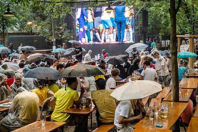 Unwetter &uuml;ber M&uuml;nchen: Starkes Gewitter mit Wolkenbruch beim Public Viewing im Augustinerkeller. Die Fu&szlig;ballfans harren beim Spiel Brasilien-Japan zun&auml;chst noch unter Regenschirmen aus.