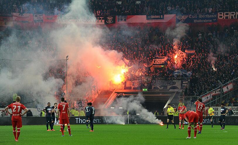 Schon vor dem Platzsturm sorgten die Anhänger in Düsseldorf für Ärger und warfen Pyrotechnik auf den Rasen. Berlins Spieler versuchen, die Massen zu beruhigen.