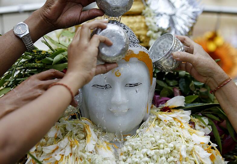 Buddhistische Gläubige gießen in Yangon Wasser über eine Buddha Büste. In Myanmar feiern die Menschen heute den Neujahrstag.