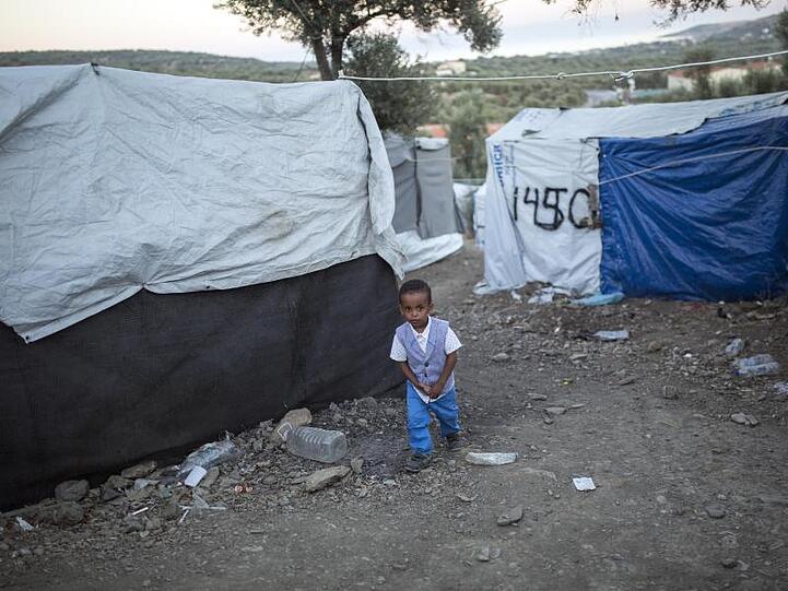 Ein Kind wandert in einem provisorischen Lager neben dem Flüchtlingslager Moria zwischen den Zelten entlang.