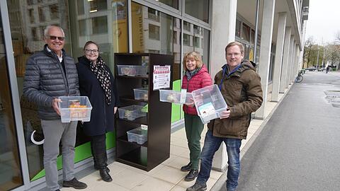 Georg Ashton (Grüne, v.l.), Lisa Schäfer von GeQo, Gabriele Lukschik und Philipp Borsch vom Verein Foodsharing befüllen das Tauschregal vor dem Café GeQo am Maria-Nindl-Platz in Bogenhausen.