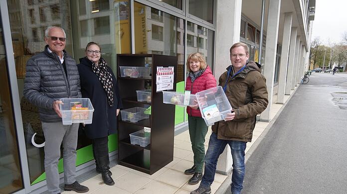 Georg Ashton (Grüne, v.l.), Lisa Schäfer von GeQo, Gabriele Lukschik und Philipp Borsch vom Verein Foodsharing befüllen das Tauschregal vor dem Café GeQo am Maria-Nindl-Platz in Bogenhausen.