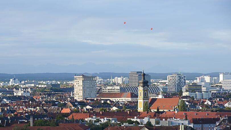Ende September 2021 lässt Immobilien-Investor Ralf Büschel zwei rote, vier Meter dicke Helium-Ballons über den Münchner Dächern fliegen, genau in 155 Metern Höhe. Sie sollen zeigen, wie weit die geplanten Türme bei der Paketposthalle in den Himmel ragen würden. Der Bau hätte 2023 schon beginnen sollen.