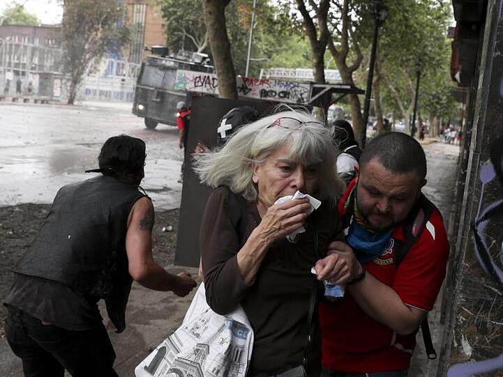 Flucht vor dem Tränengas: Angesichts der gewalttätigen Ausschreitungen in Chile hat Präsident Pinera den Nationalen Sicherheitsrat einberufen.