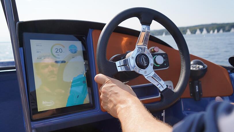 Krasse Technik, simple Anzeige: Ein aktuelles Tempo von 20 Knoten zeigt der Bildschirm neben dem Steuerrad an. Daneben: die Karte des Starnberger Sees und den Ladezustand des Akkus. Krasse Technik, simple Anzeige: Ein aktuelles Tempo von 20 Knoten zeigt der Bildschirm neben dem Steuerrad an. Daneben: die Karte des Starnberger Sees und den Ladezustand des Akkus.