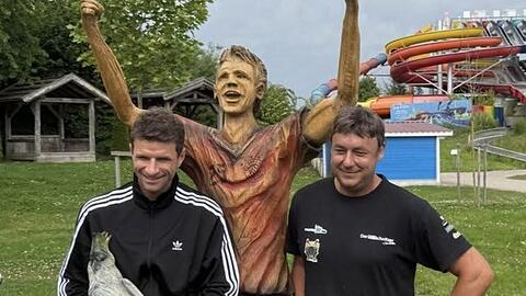 Fußballprofi Müller (l.) freut sich über die Holzskulptur, die Wastian in Handarbeit geschaffen hat.