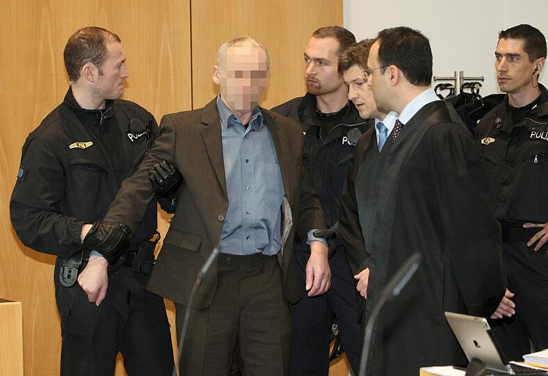 Der wegen Mordes an einem Polizisten angeklagte Raimund M. (2.v.l.) wird am Donnerstag (21.02.13) im Landgericht in Augsburg vor Beginn des Prozesses in den Verhandlungssaal gefuehrt.