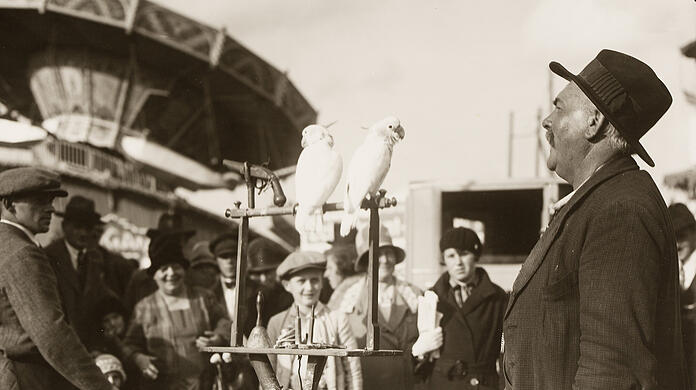 Die Wiesn im Jahr 1921: Ein Schausteller steht mit Papageien auf dem Festgelände.