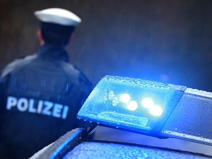 Ein Polizist steht vor einem Streifenwagen mit Blaulicht. Foto: Karl-Josef Hildenbrand/dpa/Archivbild