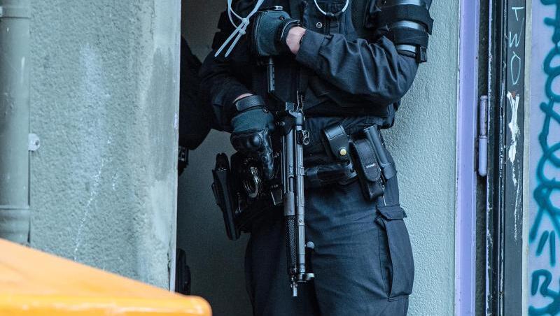 Ein bewaffneter Polizeibeamter steht an einem Wohnhaus.