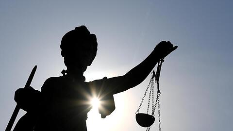 Eine Statue der Justitia mit einer Waage und einem Schwert in ihren Händen.