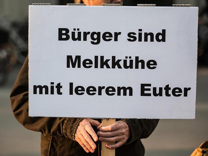 Ein Bürger demonstriert mit einem Plakat mit der Aufschrift "Bürger sind Melkkühe mit leerem Euter" gegen Abgabenlast.