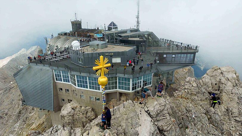 Wanderer besteigen das originale Gipfelkreuz auf der Zugspitze.