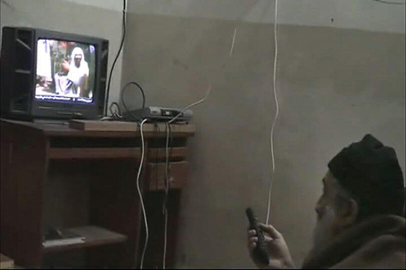 Die Szene aus einem vom Pentagon freigegebenen Video zeigt Osama bin Laden vor einem Fernseher mit einer Fernbedienung in der Hand.