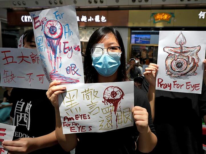 Demonstranten halten in der Ankunftshalle des Flughafens Schilder hoch. Mit dem Airport von Hongkong hat einer der verkehrsreichsten Flughäfen der Welt ein zweites Mal innerhalb von zwei Tagen den Betrieb eingestellt.