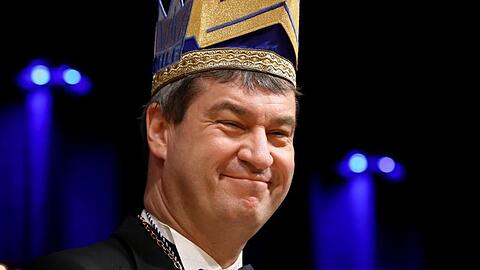 Ministerpräsident Markus Söder (CSU) trägt eine Narrenkappe und lächelt. Foto: Daniel Karmann/dpa/Archivbild
