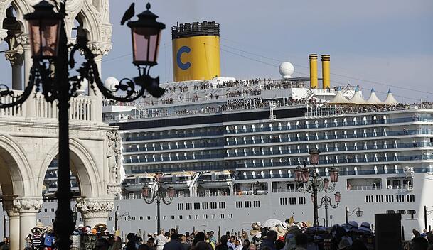 Das Kreuzfahrtschiff "Costa Deliziosa" fährt am Markusplatz vorbei, auf dem zahlreiche Touristen unterwegs sind.