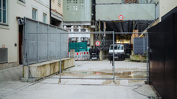 Durch die wenigen Gucklöcher, die am Bauzaun noch geblieben sind, ist nicht viel zu erspähen, außer einem Kleinbus, Containern, Absperrgittern und Baumaterial. Durch die wenigen Gucklöcher, die am Bauzaun noch geblieben sind, ist nicht viel zu erspähen, außer einem Kleinbus, Containern, Absperrgittern und Baumaterial.