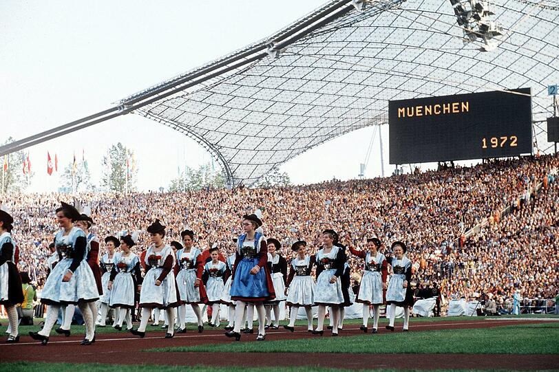 Hostessen in Tracht marschieren ins Olympiastadion ein.